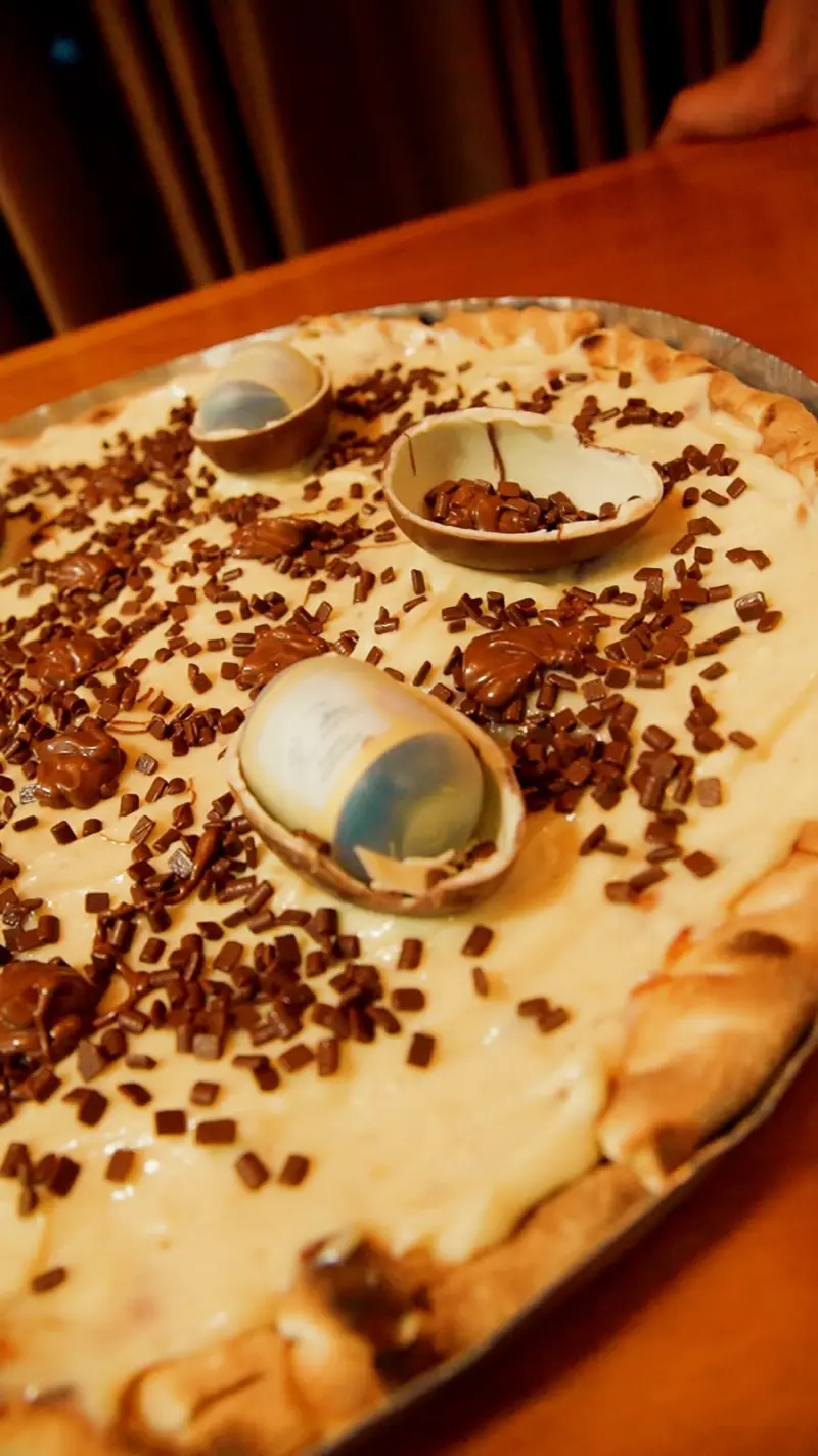 Pizza de Kinder Ovo® da Baldonni na travessa, com metades de Kinder Ovo, brigadeiro e granulé de chocolate